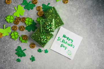 Decorative clover leaves, green gifts box, coins on stone background, flat lay. St. Patrick's Day...