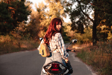 Confident woman looking over shoulder at camera sitting on motorcycle