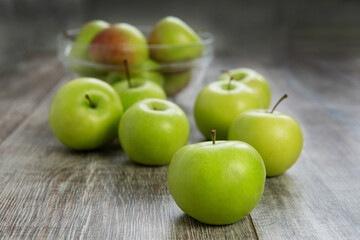 green apples on a wooden table and plate