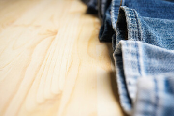 Various jeans pants on wooden background, place for text. Close-up.