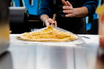 Turmeric pizza base with olive oil and a spinach leaf