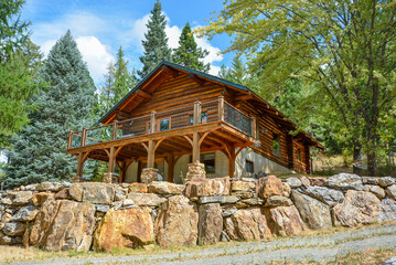 A picturesque vacant and rustic log home in the mountains surrounded by pine trees on a rocky...