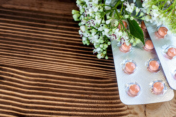 Fresh (Valeriana officinalis) flowers and Pills valerian on wooden background. Used as an alternative to valium in natural medicine, Close up. Flat lay. Copy space.