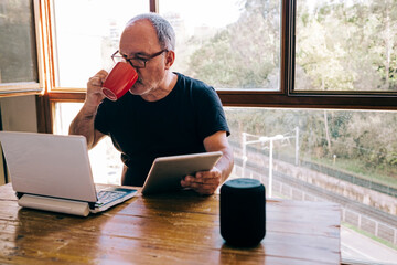 Mature man drinks from a cup while working at home