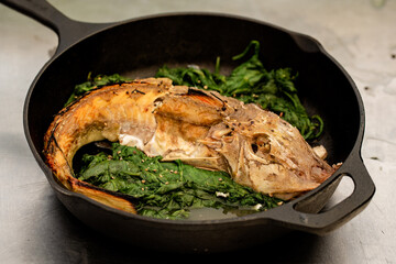 whole fish on a bed of spinach in a cast iron pan