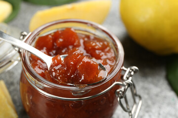Delicious quince jam and fruits on grey table, closeup