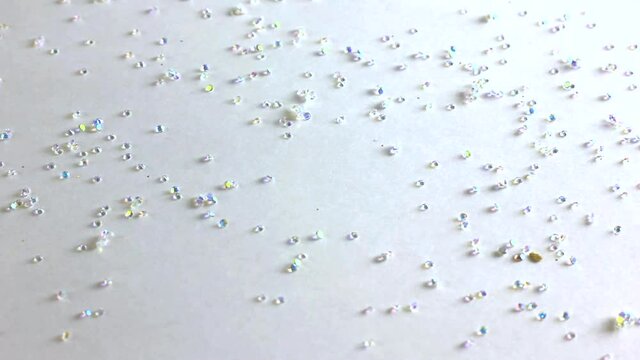 white sparkling rhinestones falling from above on white background close up
