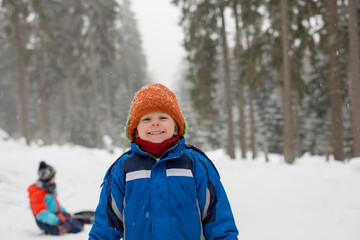 Fototapeta na wymiar Beautiful toddler child, blond boy with cute hat, playing in the snow