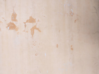 A wall with cracks and spots on the pink plaster. Not seamless texture