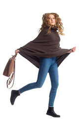 Full length portrait of beautiful stylish girl in fashion blue jeans and poncho with long curly hair posing - isolated on white background. Fashion model posing at studio. leather backpack in hand