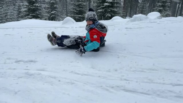 Happy children, going down the slope on a plastic sledge, speeding, happiness