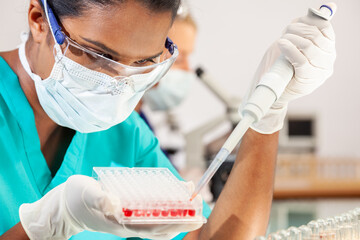 Asian Female Scientist Wearing Face Mask With Blood Sample In Laboratory