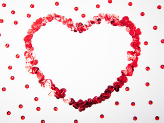 Heart shape made of heart objects and red crystals on white background with copy space, happy valentine's day, mother's day, flat lay, top view