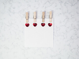 Fototapeta na wymiar Note paper with wooden clothespin and heart shape on marble background, happy valentine's day, mother's day, flat lay, top view