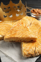 Traditional galette des Rois with paper crown on table, closeup