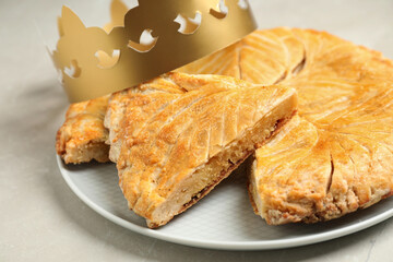 Traditional galette des Rois with paper crown on light grey marble table