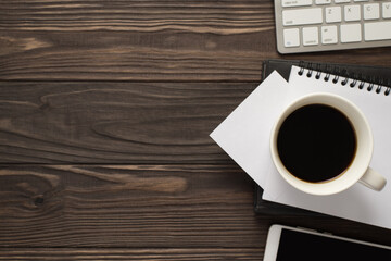 Above flat lay above view photo of strong morning beverage white piece of paper keyboard and cellphone isolated brown wooden backdrop