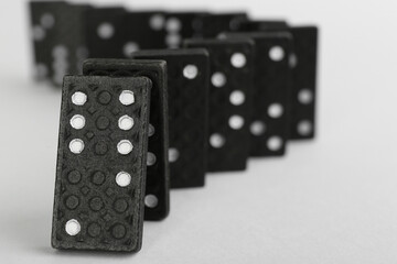 Black domino tiles falling on white background. Space for text