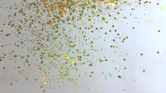 gold sequins and rhinestones pour from above and shimmer beautifully on a white background close-up, festive background