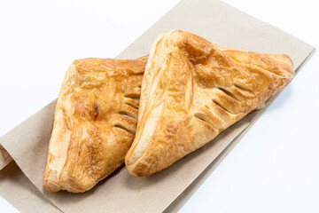 Appetizing puff pastry pies in the shape of a triangle on a paper bag