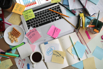 Laptop, notes and office stationery in mess on desk, top view. Overwhelmed with work