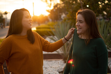 TWO WHITE WOMEN LAUGHING WITH THE SUNSET IN THE BACKGROUND
