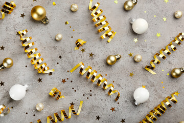 Shiny serpentine streamers and Christmas balls on grey background, flat lay
