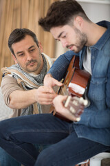 a middle aged man teacher son to play the guitar