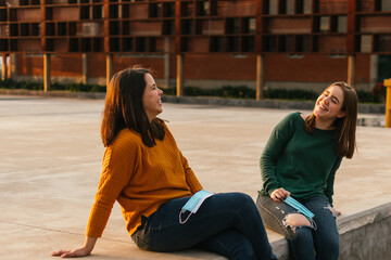 TWO WHITE WOMEN LAUGHING WITH THE FACE MASK IN HAND