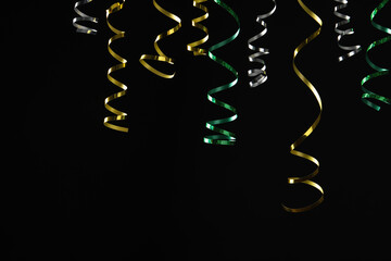 Many colorful serpentine streamers on black background