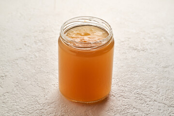 Cooled down congealed beef bone in a glass jar on a white background