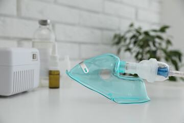 Face mask of modern nebulizer on white table. Equipment for inhalation