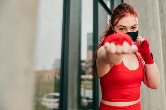 Young female boxer, training outdoors in Brooklyn wearing face-mask.