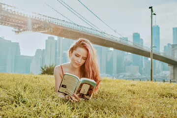 Young woman lying in park, reading book.