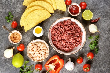 Ingredients for making tacos - ground beef, vegetables, spices, and corn shells.