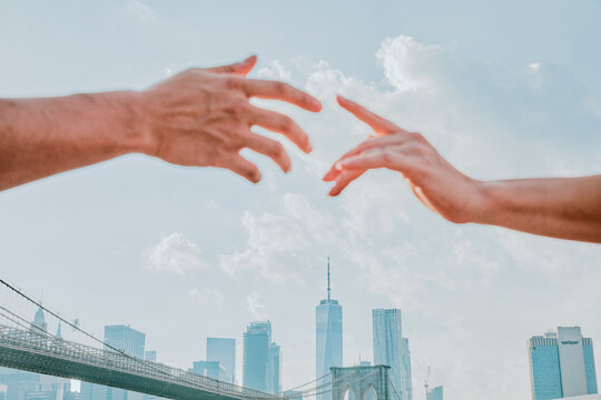 Two hands almsot touching against skyline.