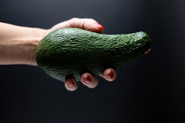 hand holding avocado Isolated on black background