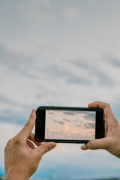 Phone taking picture of clouds at sunset.