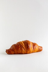 A single freshly baked croissant on a white background with copy space