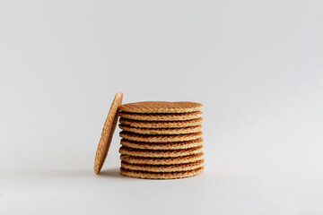 A stack of Dutch stroopwafels (syrup or caramel waffles) with one cookie in the side on a white background with copy space