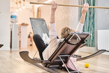 Old woman lying down doing a yoga exercise in a physiotherapy