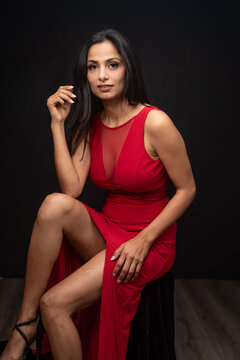 Studio images of beautiful Asian Indian woman wearing red dress on black background. 
