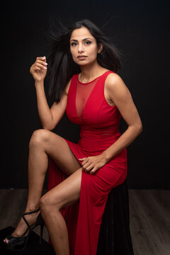 Studio images of beautiful Asian Indian woman wearing red dress on black background. 
