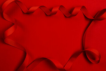 Classic red background. Ribbon`s frame. A delicate red wavy ribbon on a red background. Image for your text.