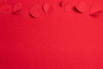Red paper hearts on a red background. Valentine's Day.