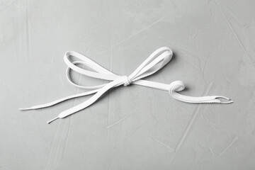 White shoelaces on light grey stone background, top view