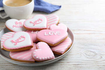 Decorated heart shaped cookies on white wooden table, space for text. Valentine's day treat