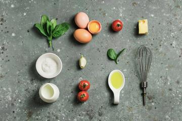 Creative mockup of ingredients for making omelet with spinach on gray concrete background. The apartment is mortgaged. Food concept.