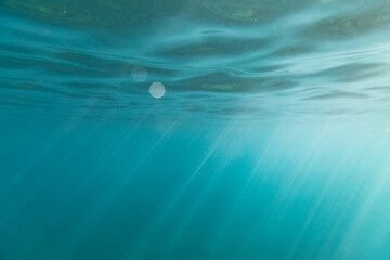 Light streaks shine through the surface of the ocean in hawaii