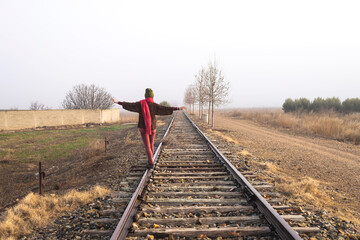 Rear view of a girl balancing on train rail while walking